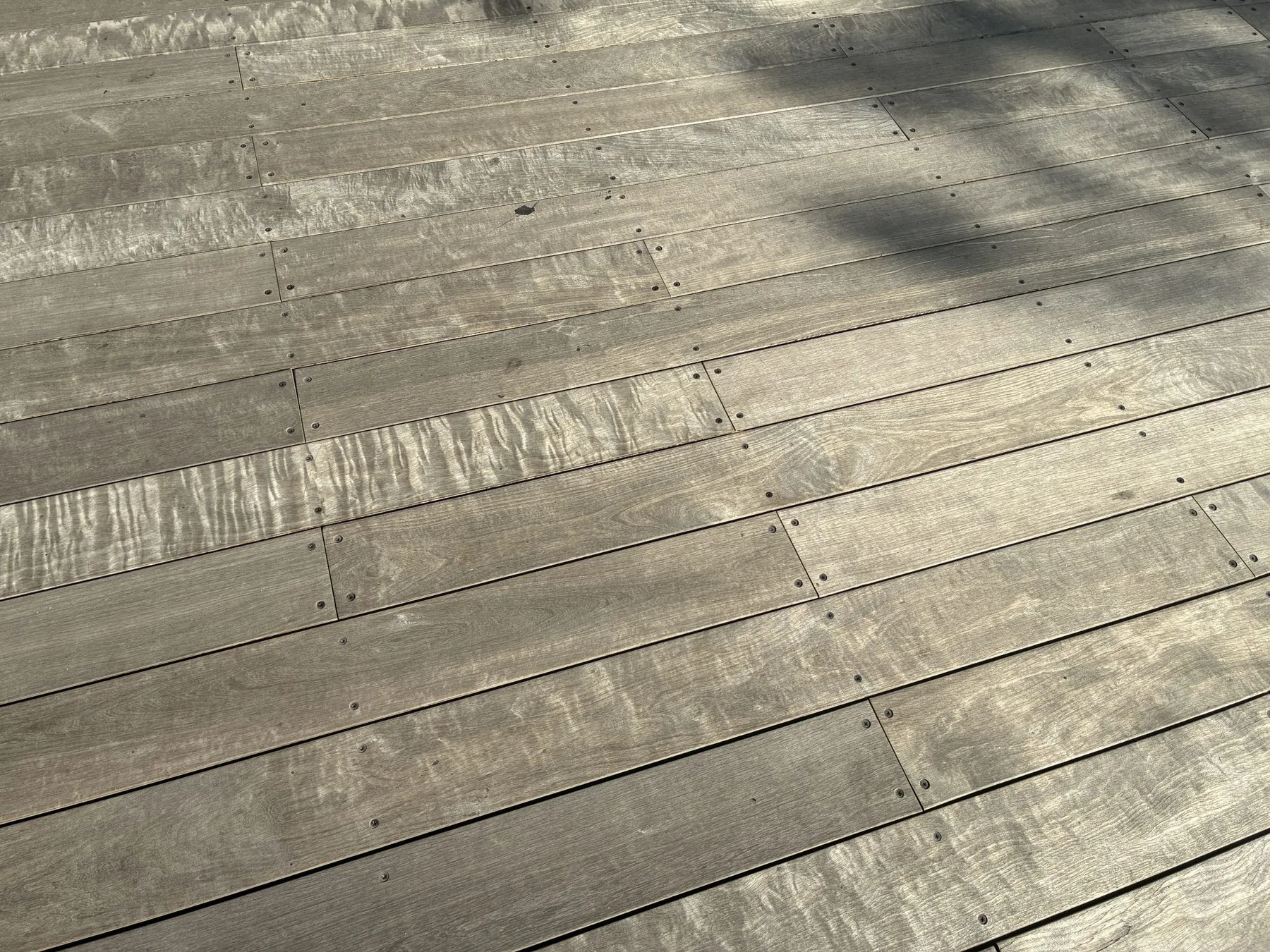 Sun-bleached gray deck boards with visible screw fixings