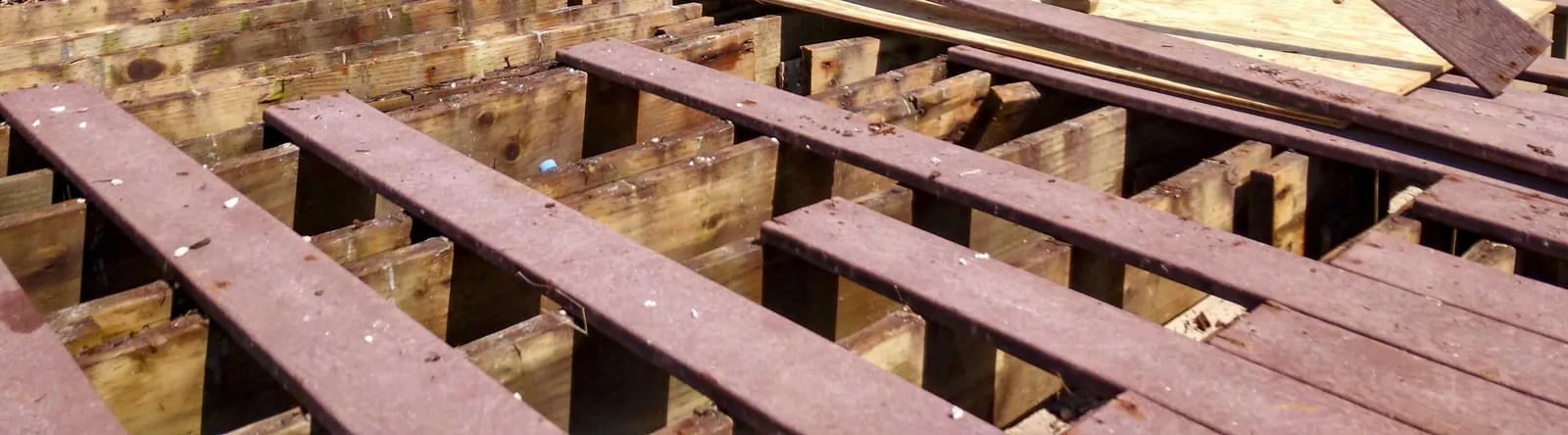 Brown composite deck boards being laid across timber joists