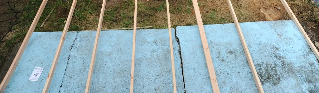 Deck joists laid out on pier blocks over an old concrete slab