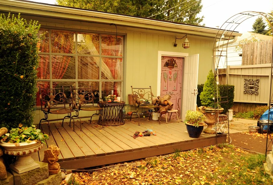 Low wooden deck along the back of a house with garden chairs