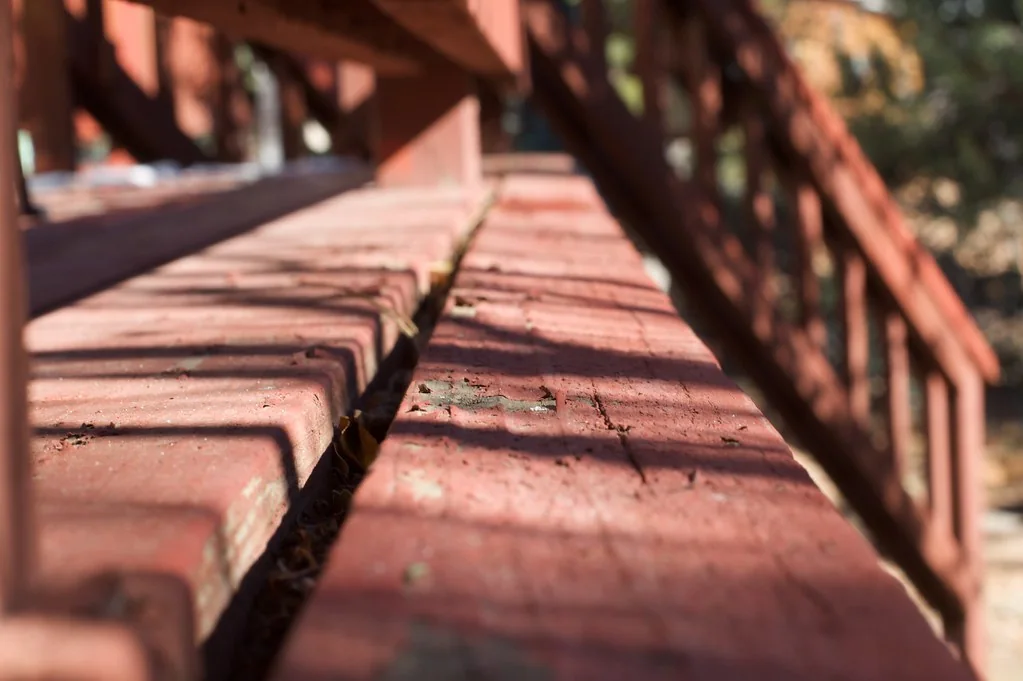 Red-painted deck steps and rail with the finish worn through