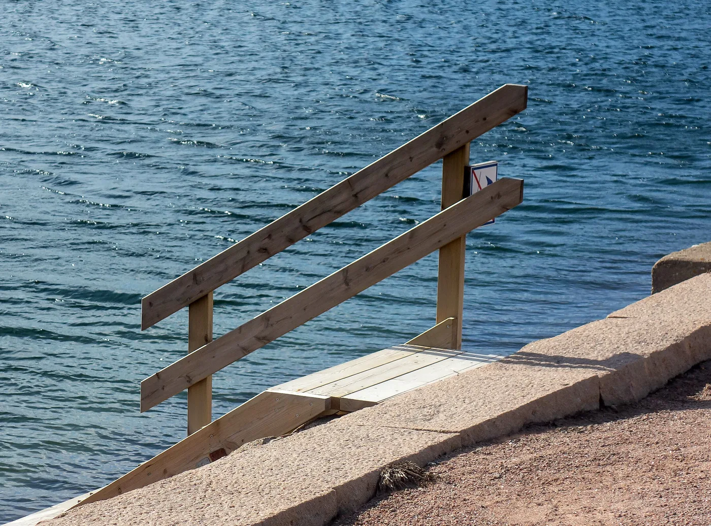 Two-rail wooden handrail beside a concrete slipway